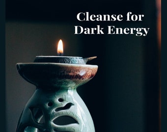 May include: A lit candle in a decorative ceramic oil burner. The burner is green and brown with a unique design. The text "Cleanse for Dark Energy" is displayed above the candle.