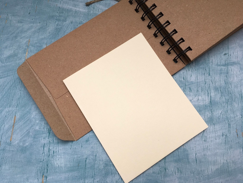 May include: A brown paper notebook with a blank white page open. The notebook is bound with a black wire coil.