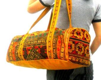 Puede incluir: Una bolsa de viaje de lona amarilla, roja y negra con estampado y una correa de cuero. La bolsa la lleva una persona con pantalones de rayas blancas y negras.