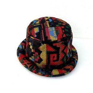 Puede incluir: Un sombrero de cubo negro con un patrón geométrico colorido. El patrón incluye rojo, amarillo, azul, verde y blanco.