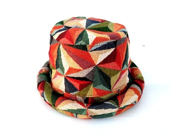 May include: A colorful geometric patterned bucket hat with a wide brim. The hat is made of a woven fabric with shades of red, orange, green, and yellow.