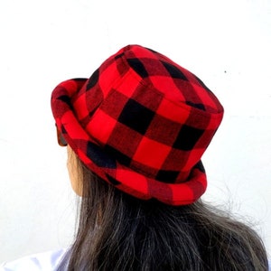 Peut inclure: Un chapeau bob en tissu rouge et noir à carreaux. Le chapeau est fait d'un tissu doux et duveteux.