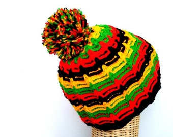 Puede incluir: Un gorro de punto rojo, amarillo y verde con un pompón negro en la parte superior.