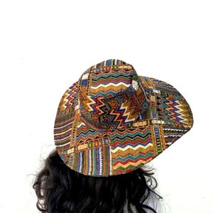 Puede incluir: Un sombrero de ala ancha con un estampado geom&eacute;trico colorido en tonos de rojo, naranja, amarillo, verde, azul y negro.