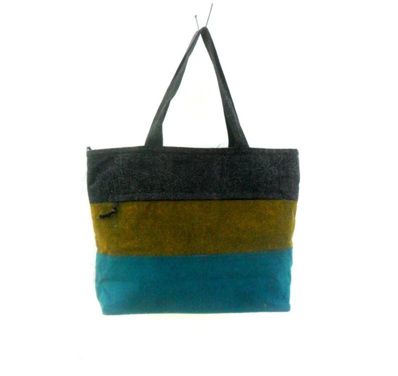 May include: A striped tote bag with a dark grey top, a brown middle section, and a teal blue bottom. The bag has two black straps.