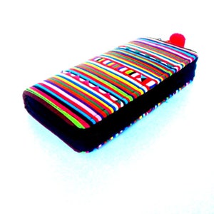 Puede incluir: Una cartera de rayas coloridas con una cremallera negra y un pomp&oacute;n rojo.