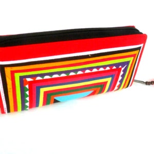 May include: A red zippered wallet with a colorful geometric pattern and a pink tassel.