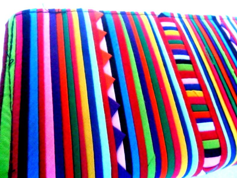 Puede incluir: Una tela de rayas coloridas con una variedad de colores, incluyendo rojo, azul, verde, amarillo y rosa. La tela est&aacute; hecha de m&uacute;ltiples tiras de tela cosidas juntas.