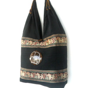 May include: Black cotton tote bag with a brown coconut shell elephant design. The bag has a brown leather strap and is decorated with a colorful elephant pattern.