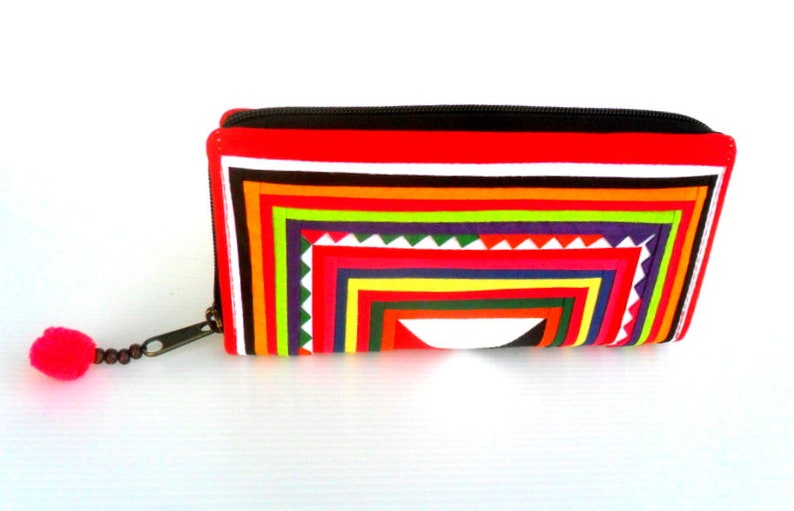 May include: A red, black, white, green, yellow, and purple striped zippered wallet with a tassel.