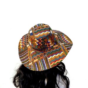 Puede incluir: Un sombrero de ala ancha con un estampado geom&eacute;trico colorido en tonos de marr&oacute;n, naranja, azul, verde y blanco.