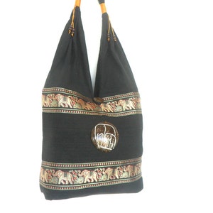 May include: Black cotton tote bag with a brown coconut shell elephant design. The bag has a gold and red trim with embroidered elephants.