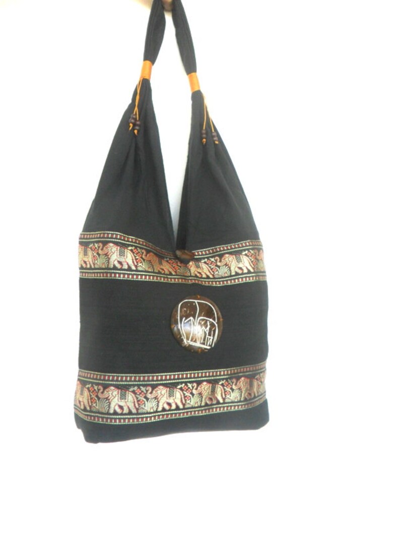 May include: Black cotton tote bag with a brown coconut shell elephant design. The bag has a gold and red trim with embroidered elephants.