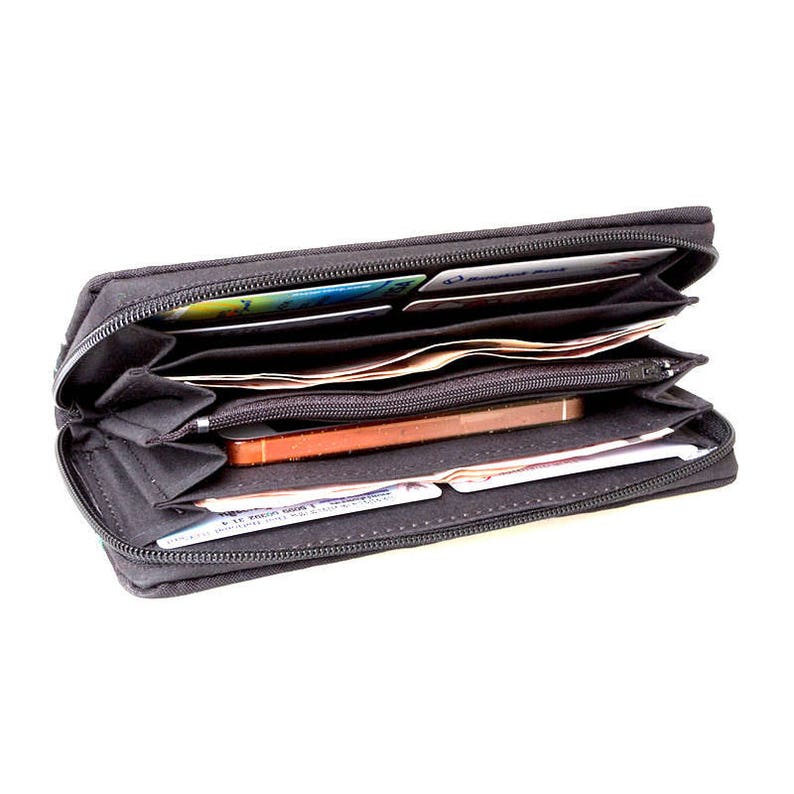 Puede incluir: Una cartera negra con cremallera con varios compartimentos, abierta para revelar efectivo, tarjetas y un tel&eacute;fono m&oacute;vil.