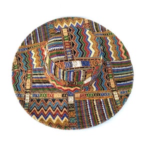 Puede incluir: Un sombrero de ala ancha con un estampado geom&eacute;trico colorido en tonos de marr&oacute;n, naranja, amarillo, azul, verde y rojo.