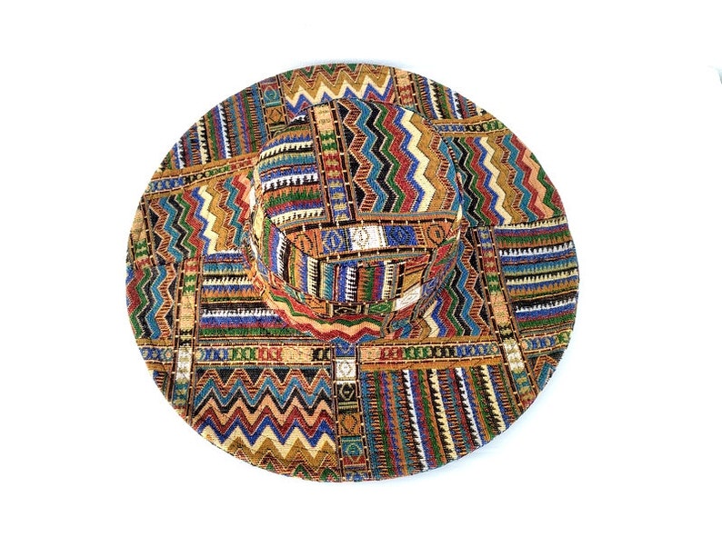 Puede incluir: Un sombrero de ala ancha con un estampado geom&eacute;trico colorido en tonos de marr&oacute;n, naranja, amarillo, azul, verde y rojo.