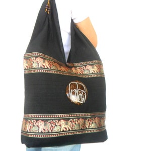 May include: Black cotton tote bag with a brown coconut shell elephant design. The bag has a gold and red trim with an elephant pattern.