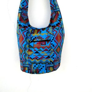 May include: A blue and red patterned shoulder bag with a zippered pocket. The bag is made of woven fabric and has a geometric design.