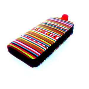 Puede incluir: Una cartera de rayas coloridas con una cremallera negra y un pomp&oacute;n rojo.