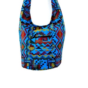May include: A blue and red patterned shoulder bag with a zippered pocket. The bag is made of woven fabric and has a geometric design.