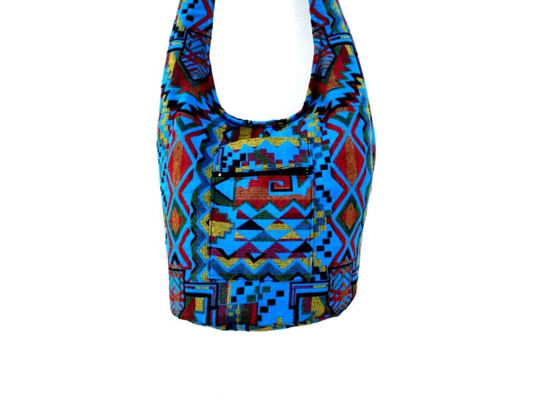 May include: A blue and red patterned shoulder bag with a zippered pocket. The bag is made of woven fabric and has a geometric design.