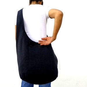 Pode incluir: Uma bolsa tote de lona preta com um bolso com z&iacute;per. A bolsa &eacute; usada no ombro e &eacute; grande o suficiente para carregar os itens essenciais do dia a dia.