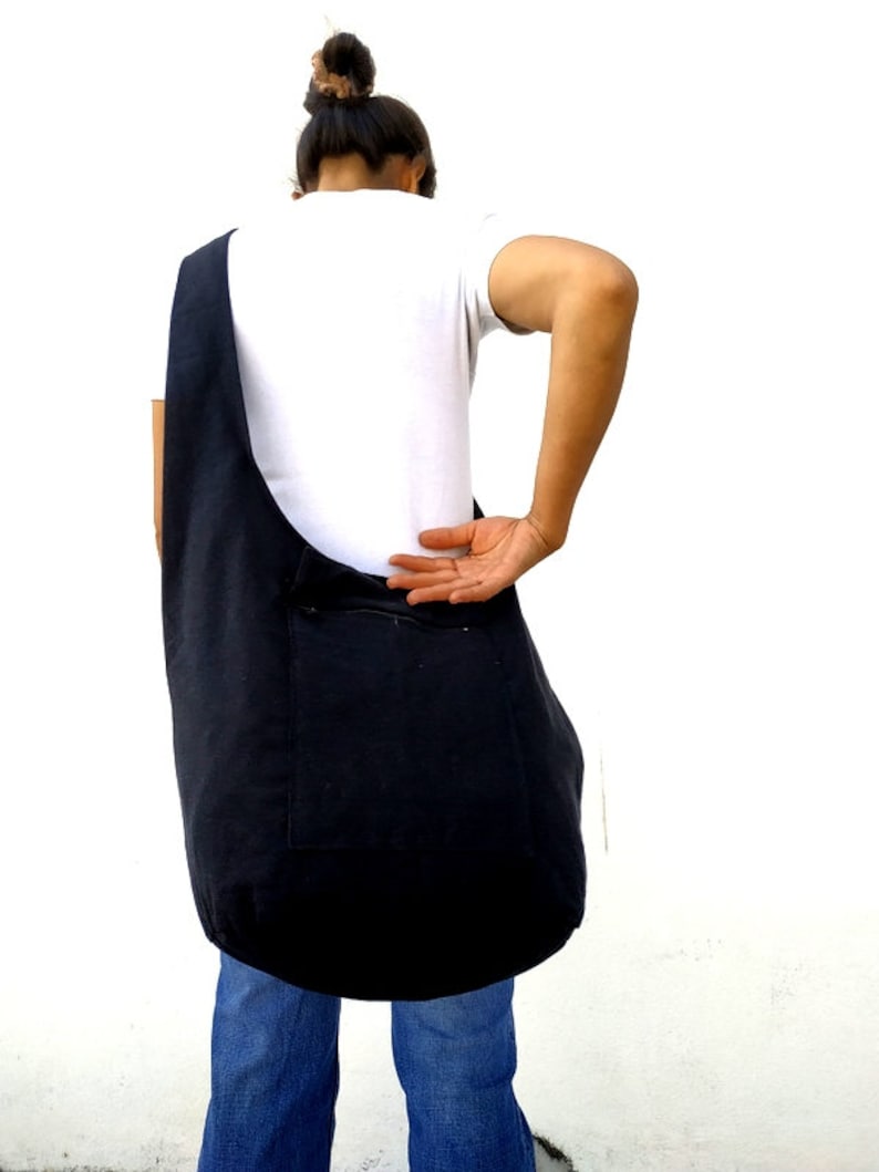 Pode incluir: Uma bolsa tote de lona preta com um bolso com z&iacute;per. A bolsa &eacute; usada no ombro e &eacute; grande o suficiente para carregar os itens essenciais do dia a dia.