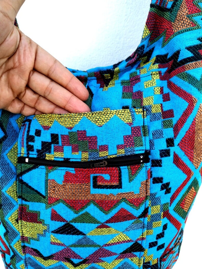 May include: A blue and multi-colored patterned tote bag with a zippered pocket. The bag has a geometric design with a variety of colors, including red, yellow, green, and black.