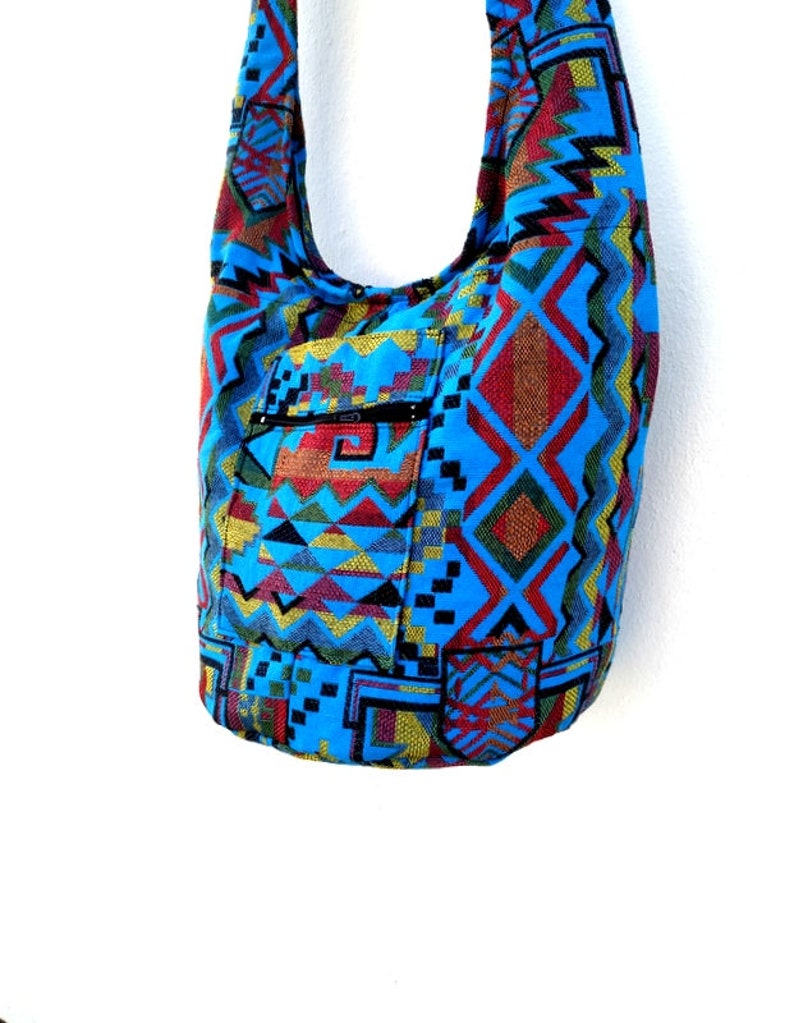 May include: A blue and red patterned shoulder bag with a zippered pocket. The bag is made of a woven fabric with geometric designs.