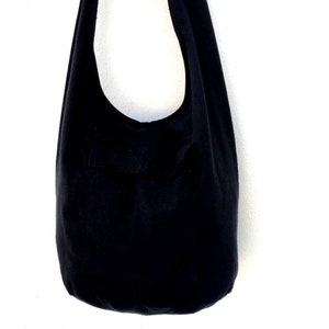 Pode incluir: Uma bolsa tote de lona preta com uma &uacute;nica al&ccedil;a. A bolsa est&aacute; pendurada em um gancho.