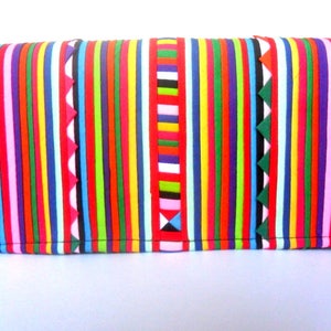 Puede incluir: Un bolso de mano de rayas coloridas con cierre de cremallera. El bolso est&aacute; hecho de un material suave y texturizado y presenta una variedad de colores brillantes, incluyendo rojo, naranja, amarillo, verde, azul, morado y rosa.