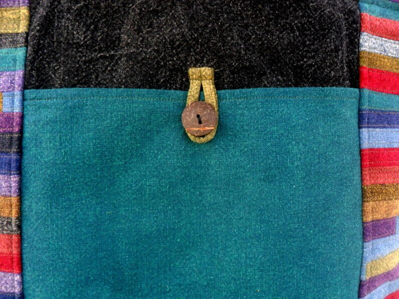 May include: A teal blue fabric bag with a brown button closure and a black fabric top.