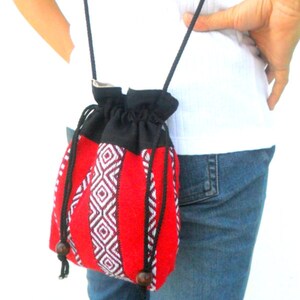May include: A red and black woven drawstring bag with a black strap. The bag has a geometric pattern and is worn over the shoulder.