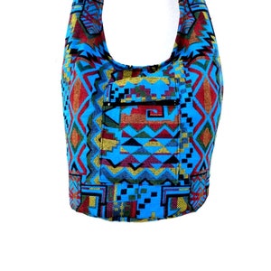 May include: A blue and red patterned shoulder bag with a zippered pocket. The bag is made of a woven fabric with geometric designs.
