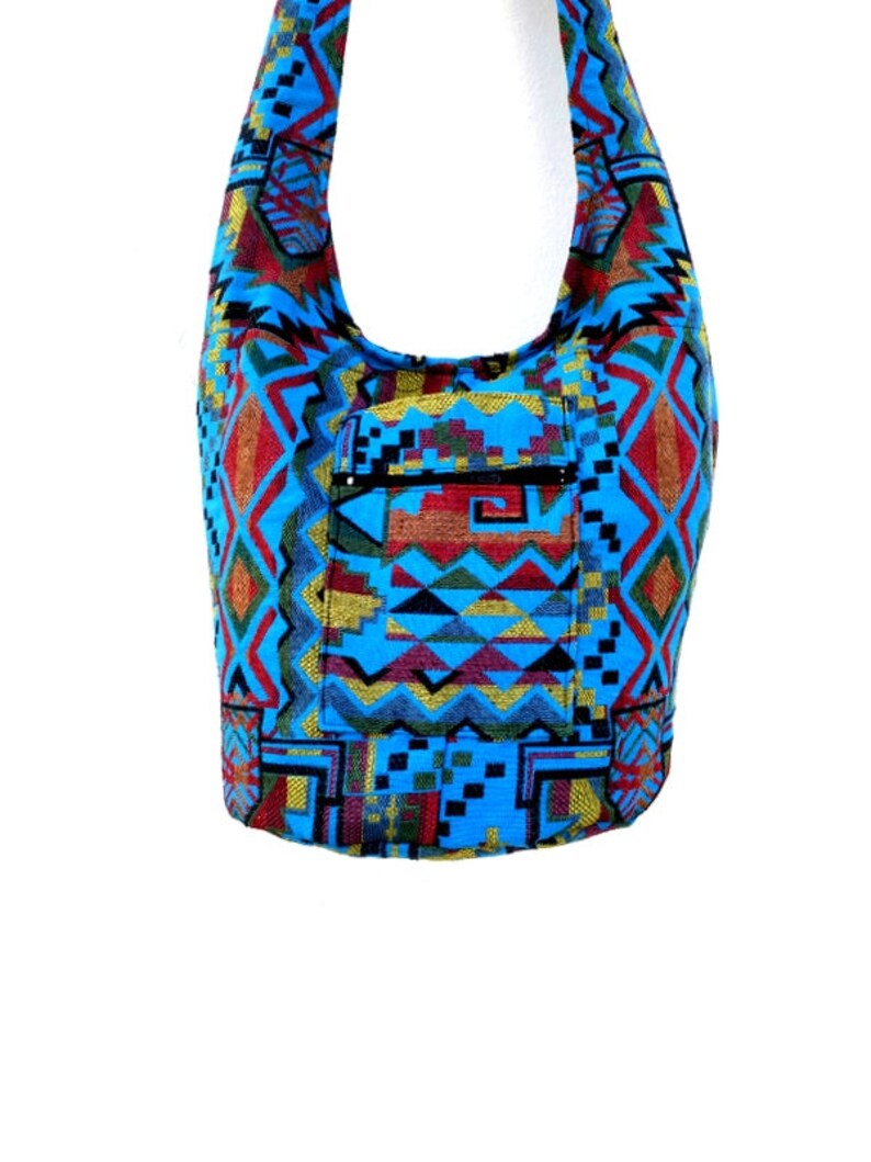 May include: A blue and red patterned shoulder bag with a zippered pocket. The bag is made of a woven fabric with geometric designs.