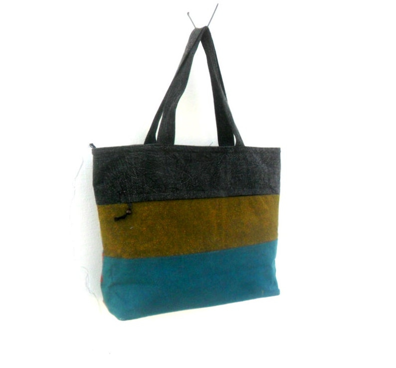 May include: A striped tote bag with a grey, brown, and teal colour scheme. The bag has two handles and a zip closure.