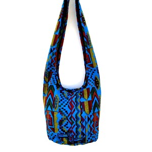 May include: A blue and multi-colored patterned shoulder bag with a long strap.