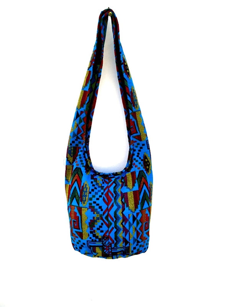 May include: A blue and multi-colored patterned shoulder bag with a long strap.