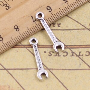 May include: Two silver-toned wrench charms, each with a loop at the top for attaching to a necklace or bracelet.