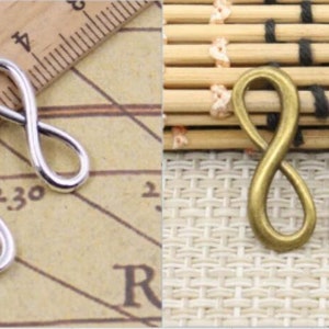 May include: Two infinity symbol charms, one silver and one bronze. The charms are about 1 inch long.