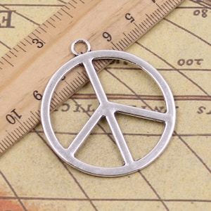 Puede incluir: Colgante de plata con forma de signo de paz con un bucle para colgar. El encanto tiene un diámetro de aproximadamente 5 cm.