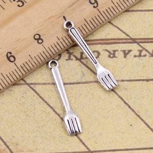 Op de afbeelding: Twee zilverkleurige metalen vorkcharms met een lus aan de bovenkant om aan sieraden of andere knutselwerken te bevestigen.
