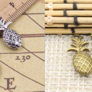 May include: Two silver pineapple charms and two gold pineapple charms. The charms are detailed with a pineapple design and have a loop at the top for attaching to jewellery or other crafts.