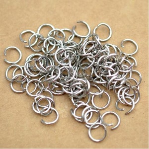 Peut inclure: Un grand tas d'anneaux de saut argentés, un type d'anneau métallique utilisé dans la fabrication de bijoux.