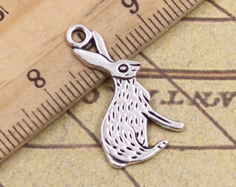 May include: A silver-toned metal rabbit charm featuring textured fur details and a small loop at the top for attachment. The charm is positioned next to a wooden ruler, showing it measures approximately 1.25 inches in total length.