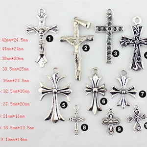May include: Ten silver-toned cross charms of various styles and sizes. The charms are arranged in a row on a white background. The charms are numbered 1 through 10, with the corresponding measurements listed below each charm.