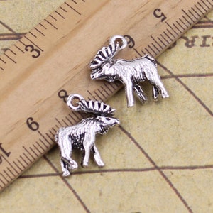 Op de afbeelding: Twee zilverkleurige elandbedels met gedetailleerde gewei. De bedels zijn ongeveer 2,5 cm hoog en perfect om sieraden of knutselwerk met een vleugje natuur te versieren.