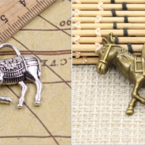 May include: Two silver donkey charms with a basket on their back. The donkey on the left is silver and the donkey on the right is bronze.