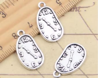 May include: Three silver-toned metal clock charms with a melted or distorted design. Each charm features a clock face with Roman numerals and hands.