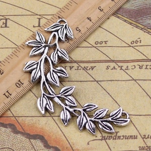 May include: Silver-toned metal leaf branch charm with a delicate design. The charm is about 6 inches long and features multiple leaves and branches.